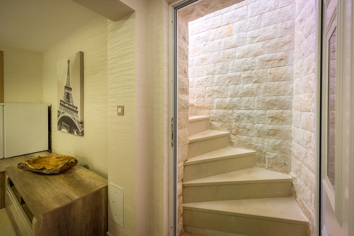 Living room of a villa in Krašići, Montenegro: stone spiral staircase, wooden furniture, and decor in a modern interior.