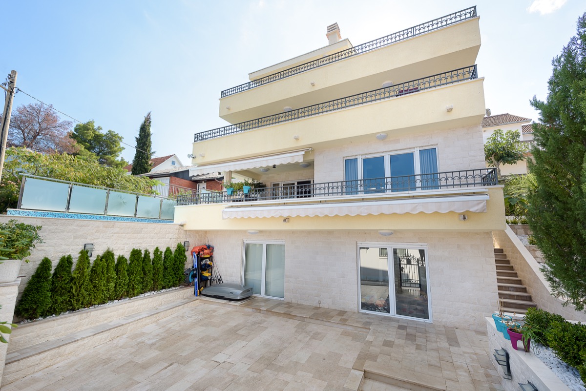 Three-story villa in Krašići, Montenegro: stone facade finish, terraces with wrought-iron railings, and a cozy courtyard.