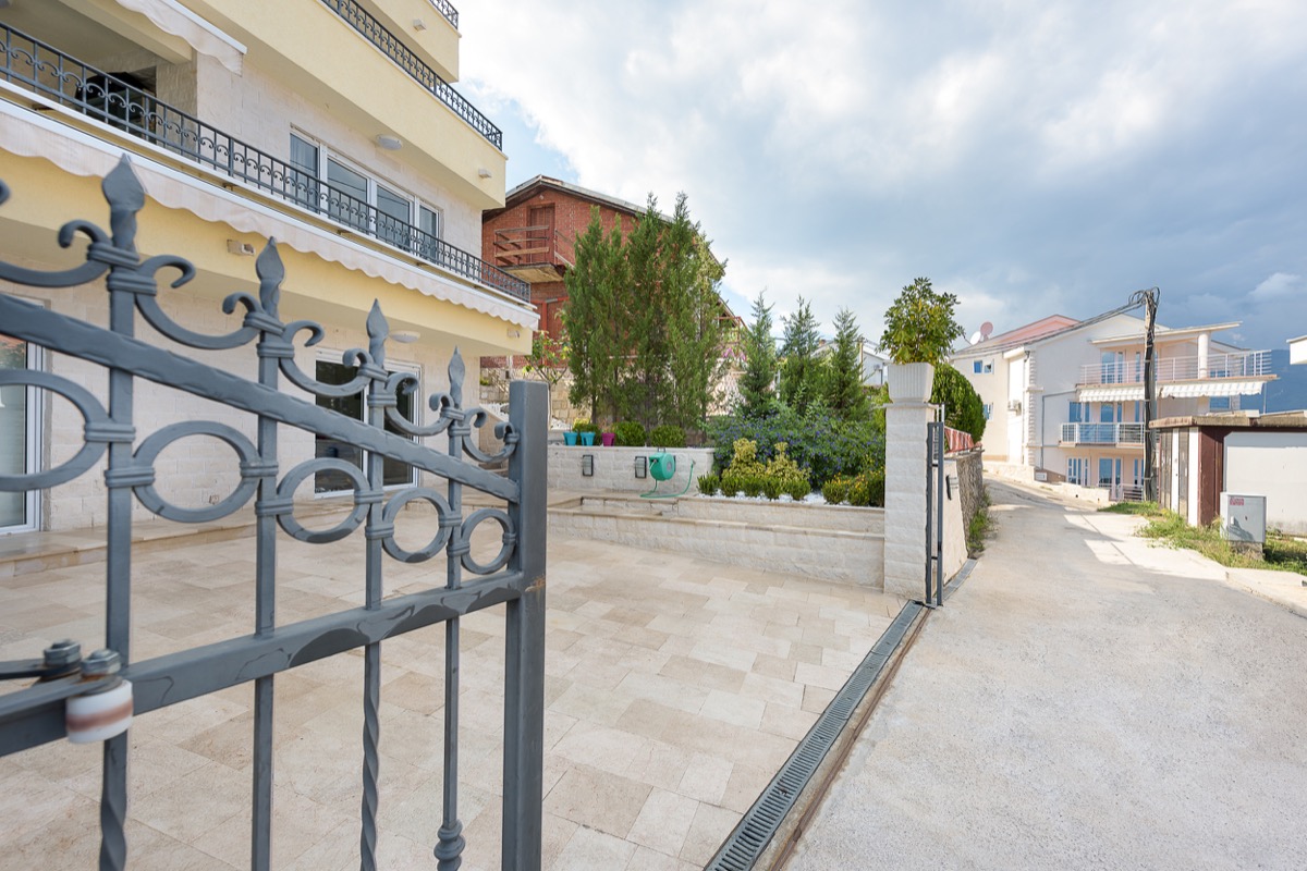 Villa in Krašići, Montenegro: view of a landscaped courtyard with wrought-iron gates, stone finishes, and a garden.