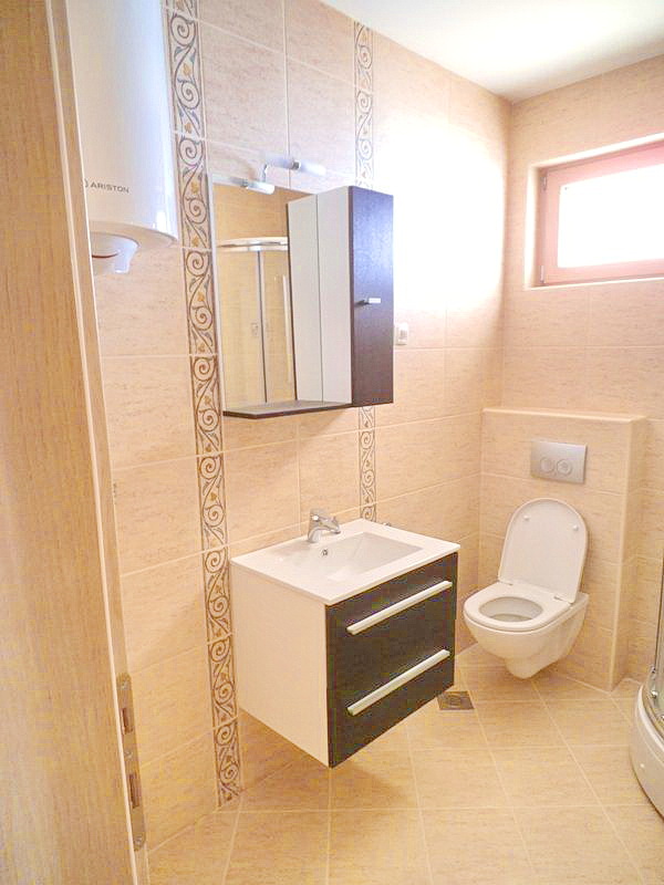 Modern bathroom in a hotel in Bečići, Montenegro: wall-mounted vanity with sink, mirror, and concealed toilet installation.