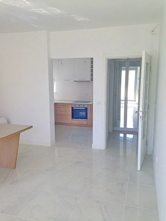 Kitchen with white upper cabinets, wooden lower units, and a built-in oven visible through an opening.