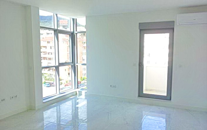 Bright living room with panoramic windows and access to the balcony in a new residential complex, Budva, Montenegro.