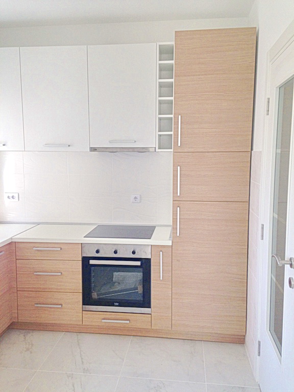 Modern kitchen with white and wood-front cabinets in an apartment in a residential complex in Budva, Montenegro.