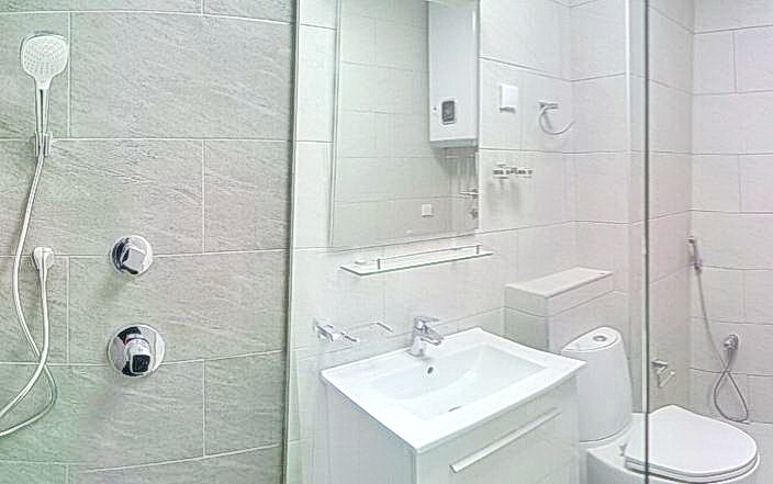 Modern bathroom with a shower cabin in a residential complex in Budva, Montenegro: light tiles and sanitary ware.