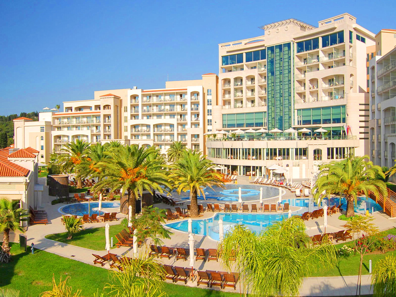 Modern residential complex with swimming pools, palm trees, and a relaxation area in Bečići, Montenegro. View of the resort area.