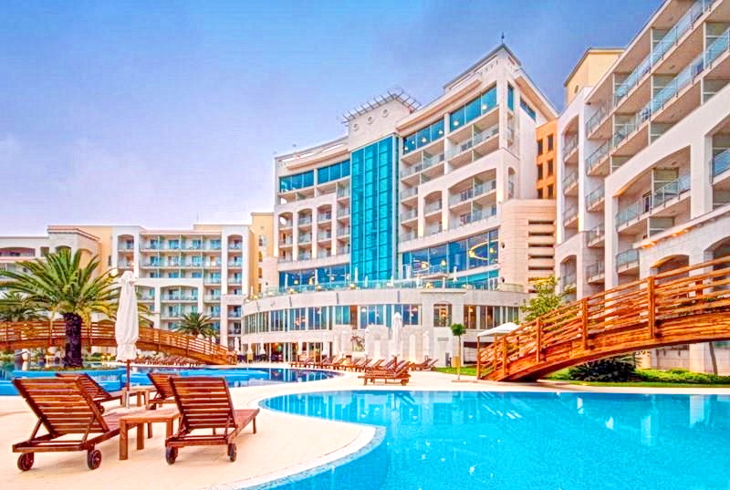 Modern residential complex with a swimming pool, sun loungers, and wooden walkways in Bečići, Montenegro.