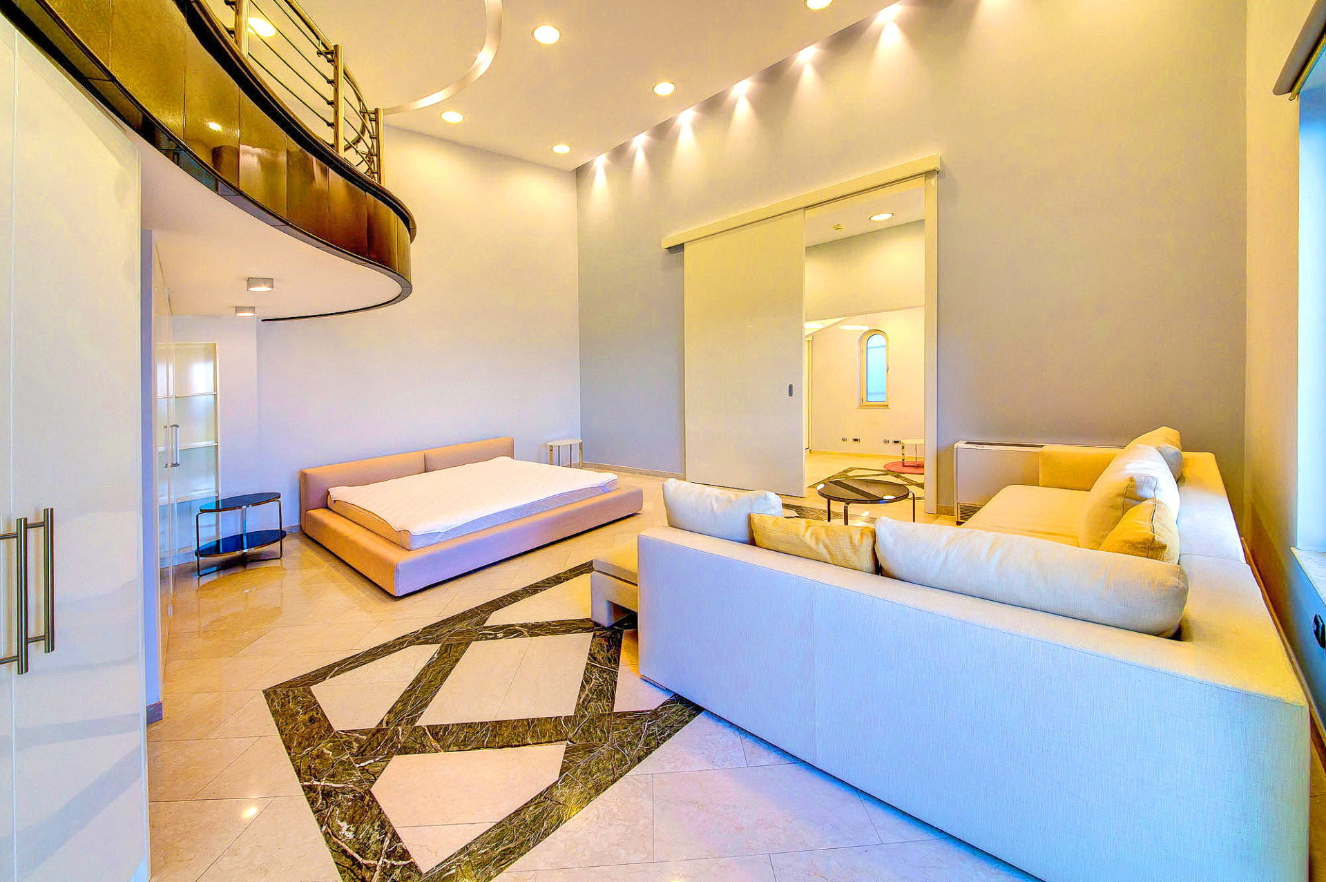 Spacious living room with a split-level layout in an apartment in Bečići, Montenegro: light-colored furniture and marble flooring.