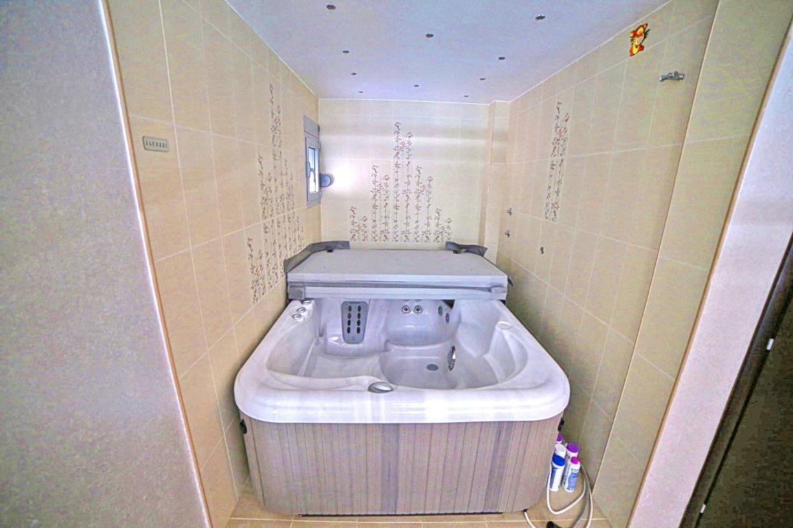 Bathroom with a jacuzzi in a villa in Budva, Montenegro: light tiles with floral decor and recessed lighting.