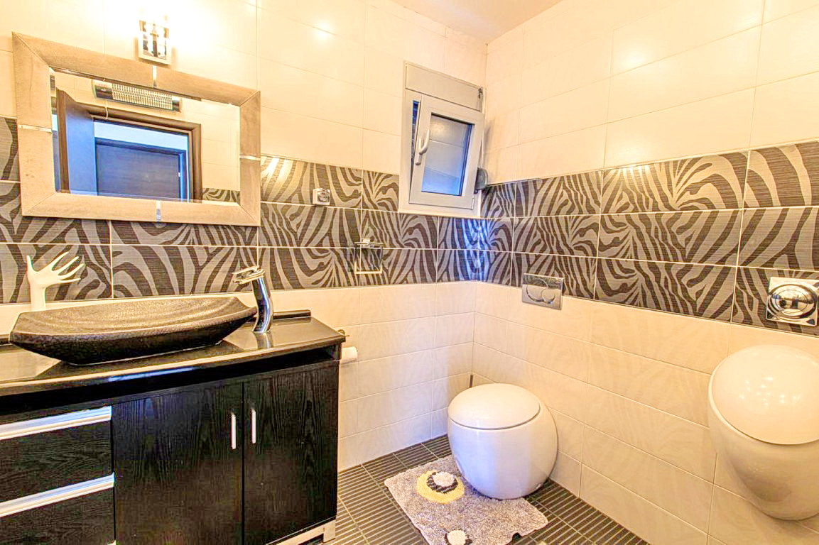 Bathroom in a villa in Budva, Montenegro: stylish fixtures, a vanity under the sink, and zebra-print tiles.