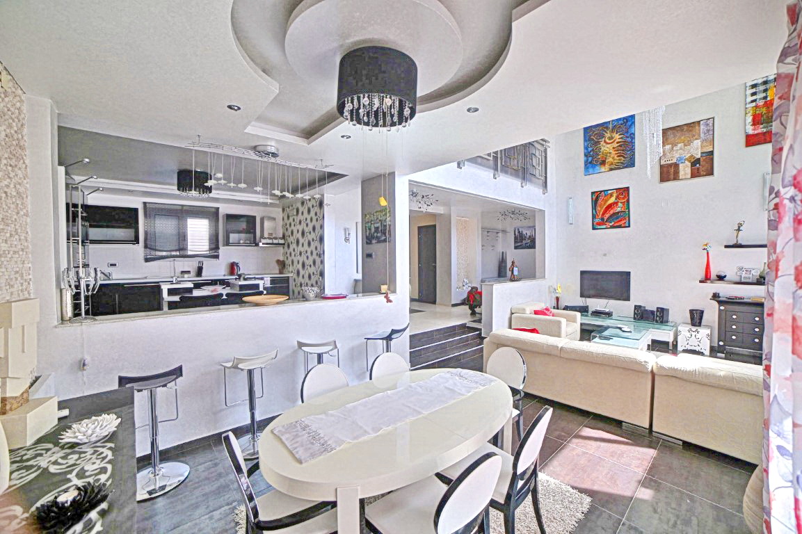 Modern living room with dining area and kitchen in a villa in Budva, Montenegro: stylish interior, high ceilings.