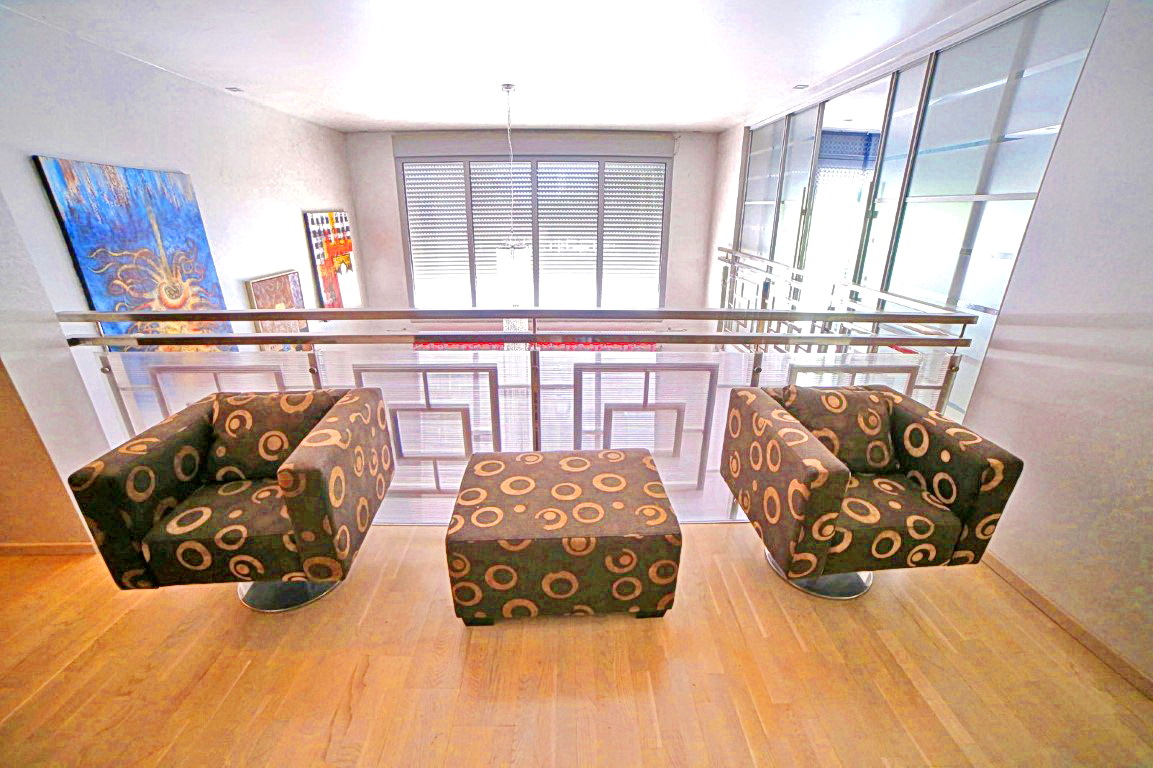 Relaxation area with armchairs in a modern villa in Budva, Montenegro: parquet flooring, panoramic windows, and stylish interior.