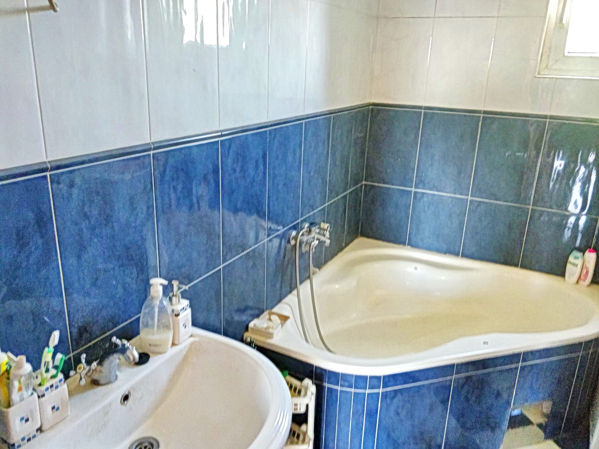 Bathroom with a corner bathtub and blue tiles in a house for sale, Podgorica, Montenegro.