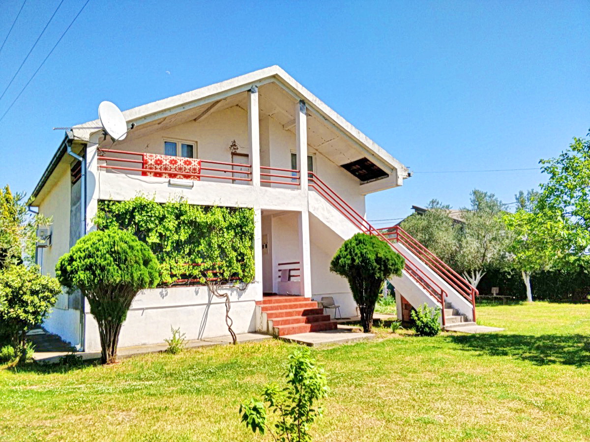 Two-story private house with a terrace and garden in Podgorica, Montenegro: facade with an external staircase and greenery.