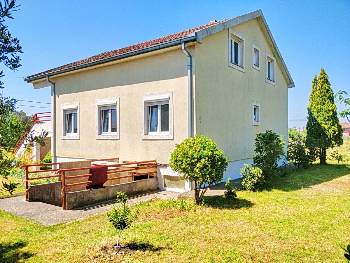 Two-story private house with a tiled roof and a green garden in Podgorica, Montenegro, front view and surrounding yard