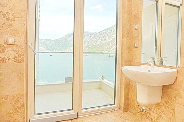 Bathroom with a view of the sea and mountains in a residential complex, Morinj, Montenegro: beige tiles and a panoramic balcony.