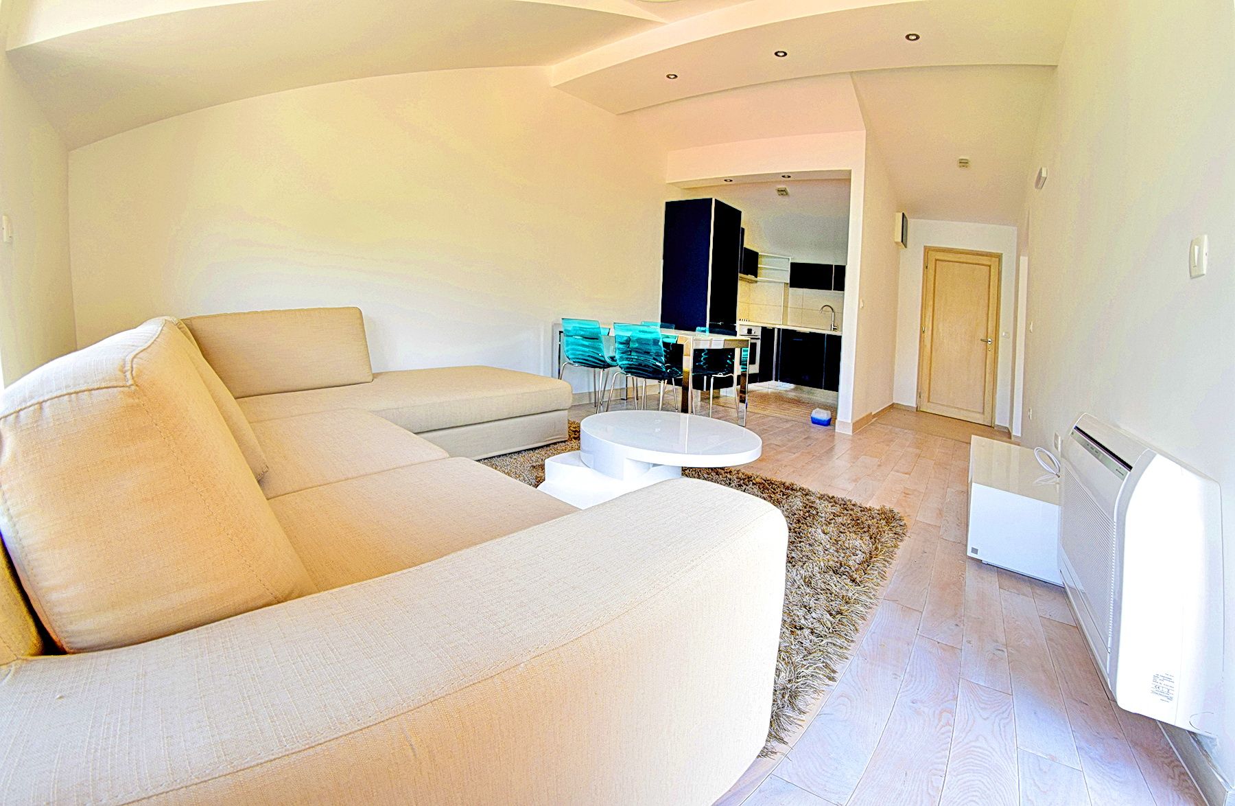 Living room with a beige sofa and kitchen in a residential complex in Morinj, Montenegro: modern interior, light tones, and stylish furniture.