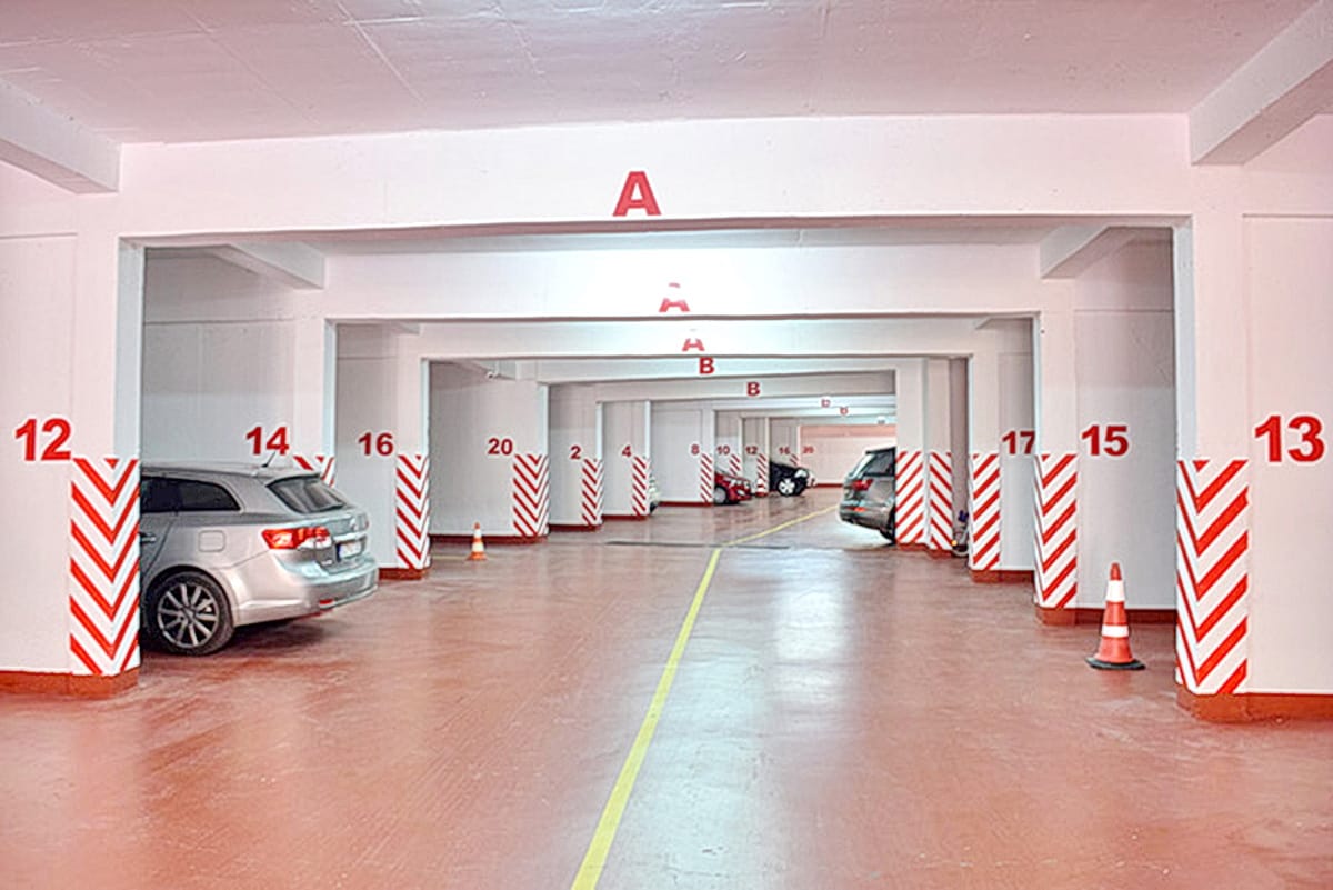 Covered underground parking in a residential complex in Morinj, Montenegro, with numbered parking spaces.