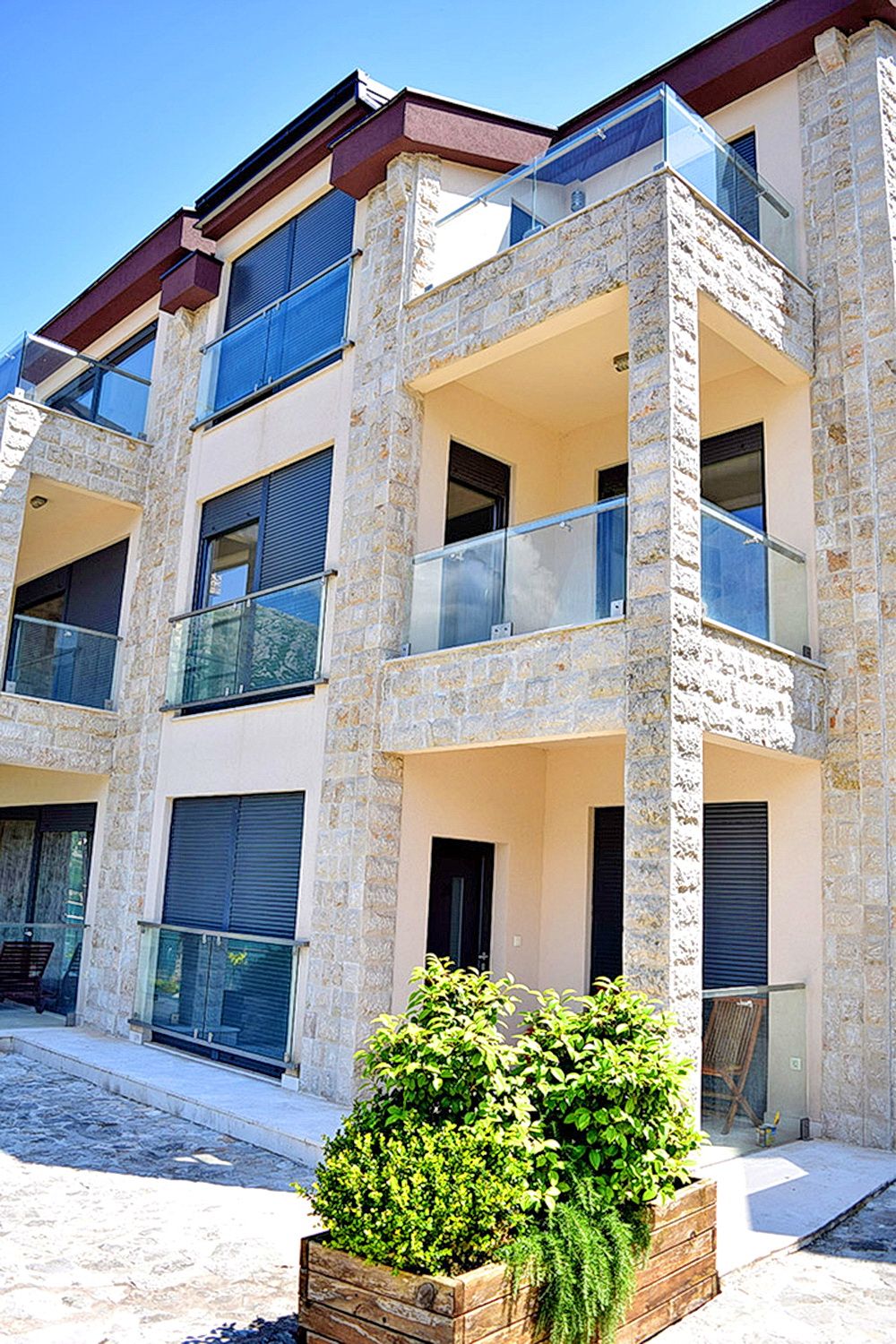 Modern residential complex in Morinj, Montenegro: natural stone facade, terraces with glass railings.