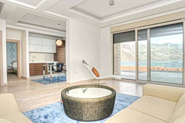Modern living room with sea view in a residential complex in Morinj, Montenegro: bright interior, panoramic windows, and kitchen.