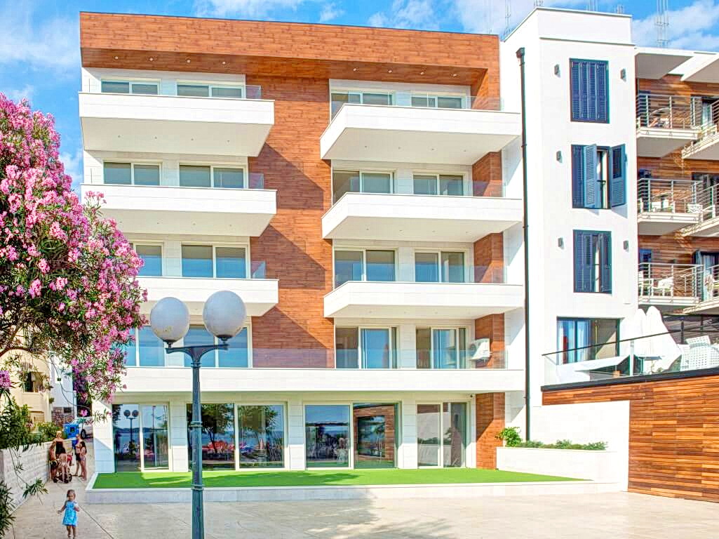Modern residential complex with balconies in Rafailovići, Montenegro: facade with wood finish and panoramic windows.