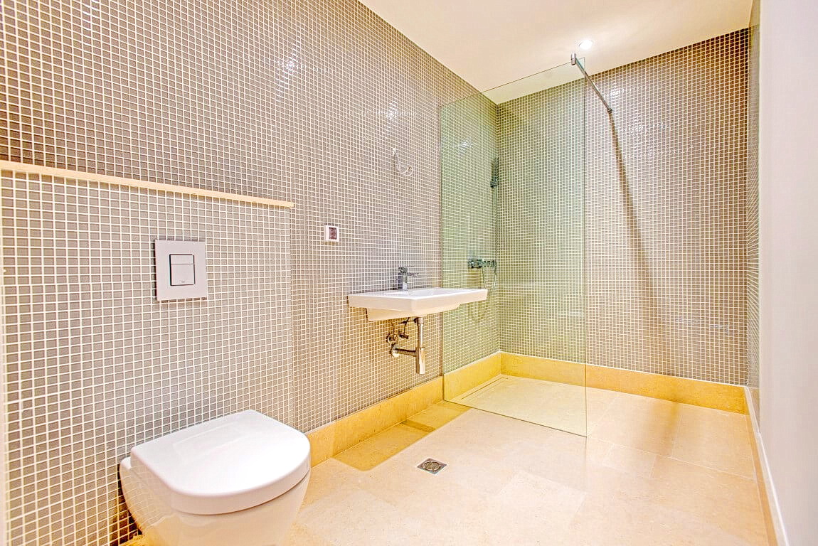 Modern bathroom in an apartment in Rafailovići, Montenegro: shower cabin, mosaic tiles, and plumbing fixtures.