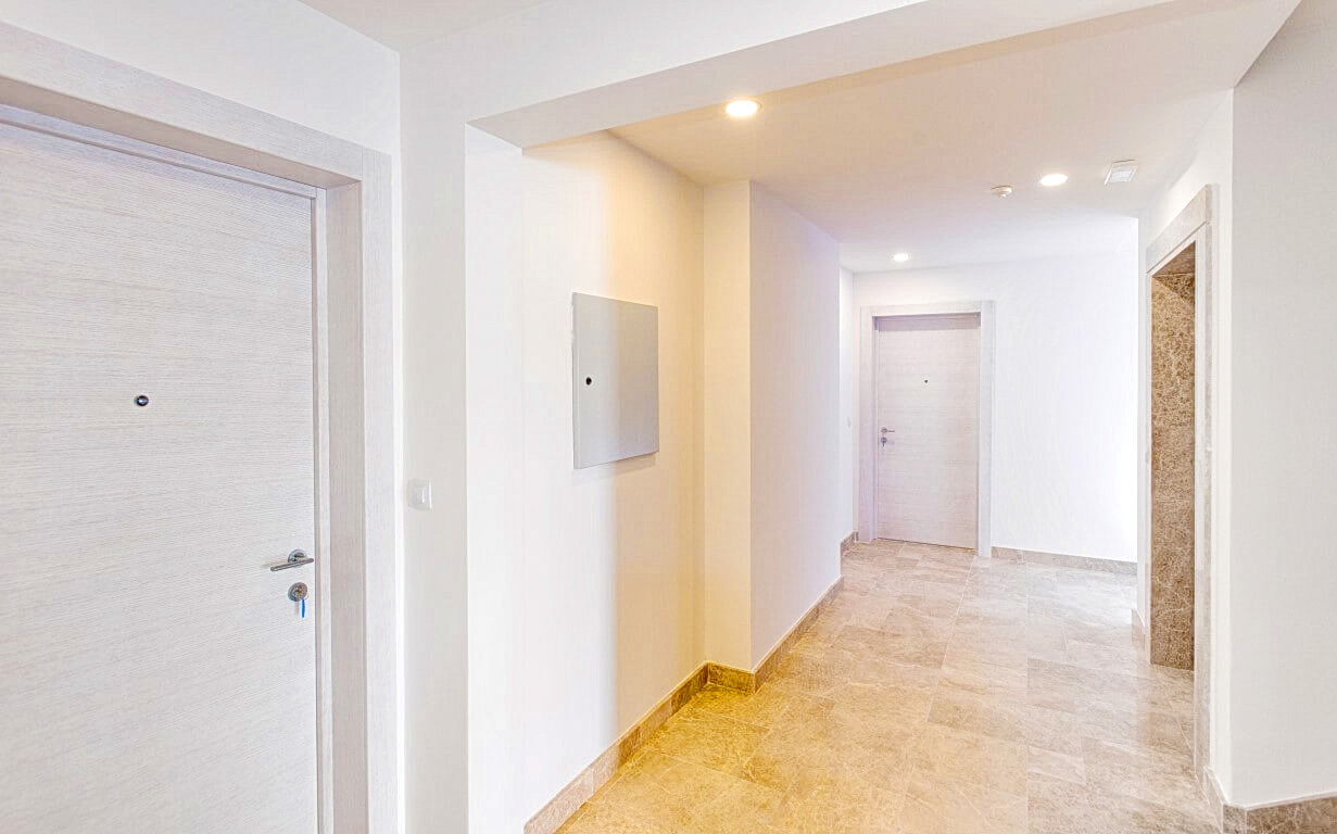 Bright hallway in a modern apartment, Rafailovići, Montenegro: high-quality finishes, stone flooring, and interior doors.