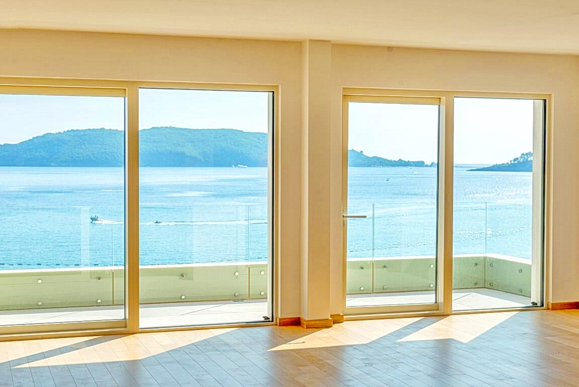 Living room with panoramic windows and sea view in an apartment, Rafailovići, Montenegro. Bright interior with a terrace.