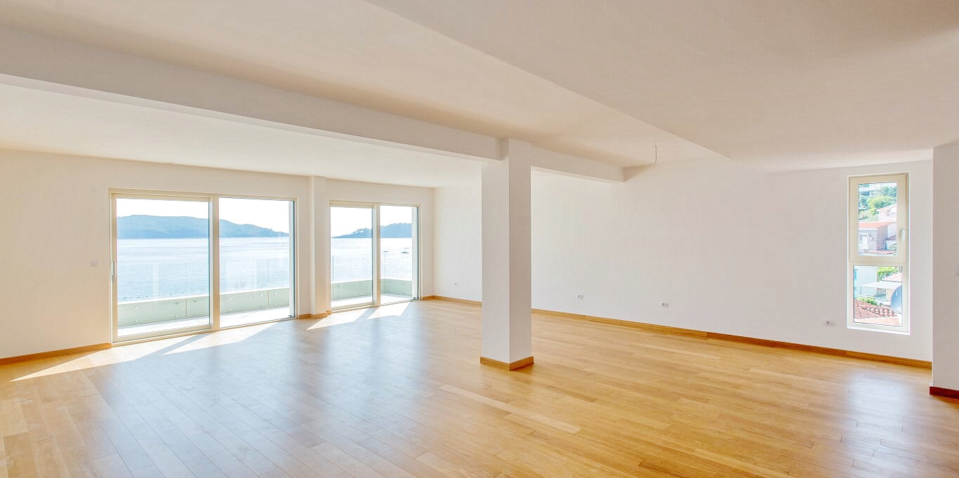Spacious living room with panoramic sea view in an apartment, Rafailovici, Montenegro: bright interior, parquet flooring.