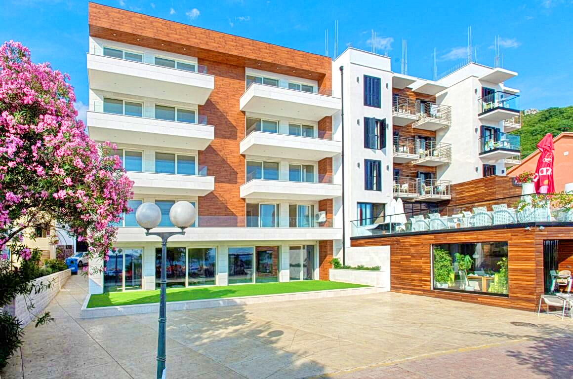 Modern residential complex with balconies and wood finishes in Rafailovići, Montenegro, front view of the building facade with a terrace.