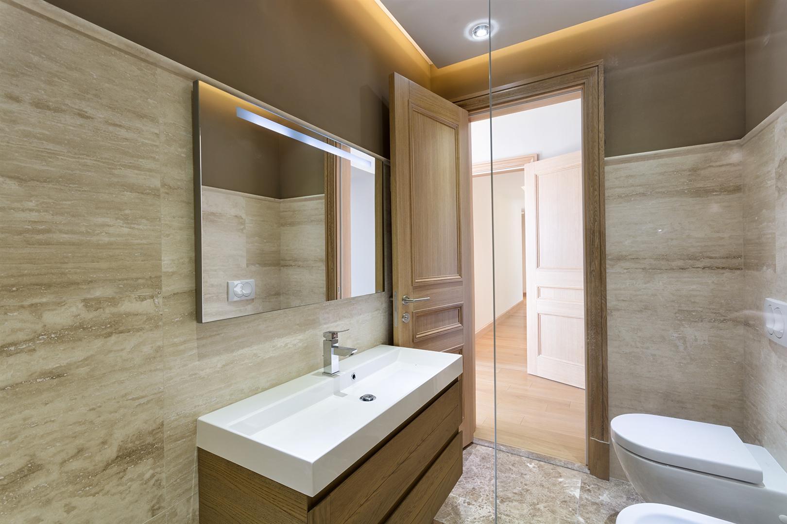 Modern bathroom with travertine finishes in Villa No. 154, Blizikuće, Montenegro: vanity, mirror, and sanitary ware.