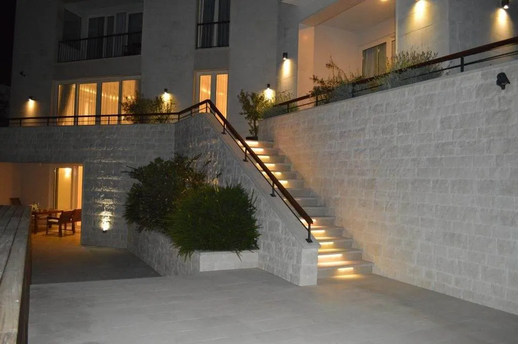 Night view of an illuminated stone staircase, terrace, and building facade.