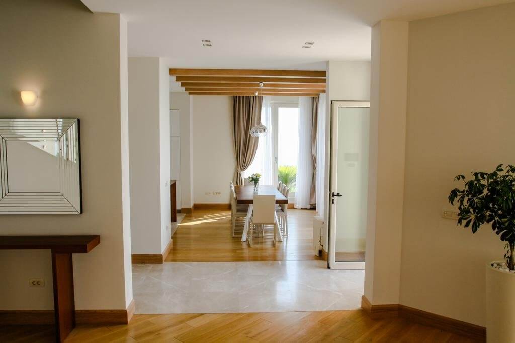 Bright living room with dining area and wooden beams in a villa in Blizikuće, Montenegro. Modern interior.