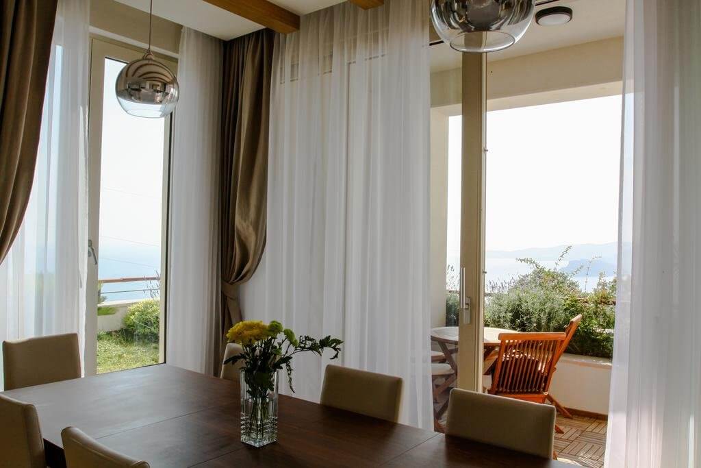 Living room with dining area and panoramic sea view in a villa, Blizikuće, Montenegro. Modern interior with a terrace.
