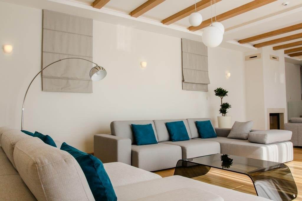 Modern living room with gray sofas and wooden beams in a villa in Blizikuće, Montenegro.