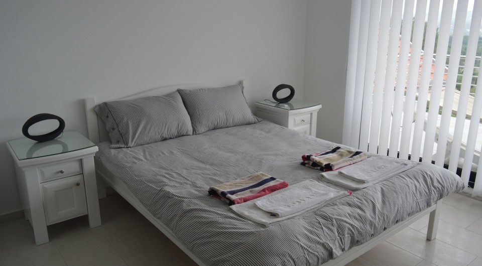 Bright bedroom with a double bed and mountain views in a villa in Tivat, Montenegro. Modern interior with white furniture.