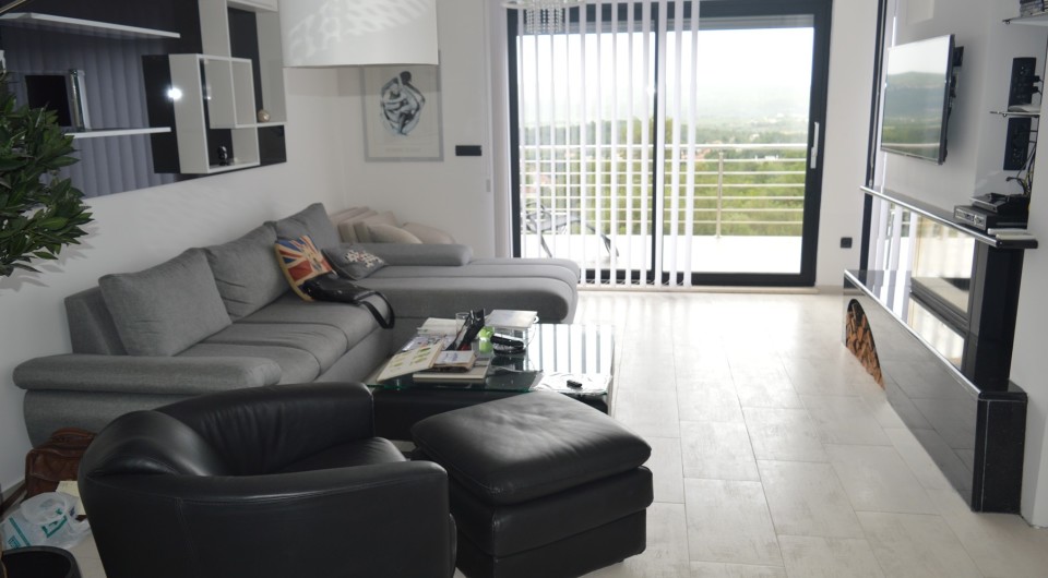 Modern living room with a fireplace and panoramic view of the terrace in a villa in Tivat, Montenegro. Interior with leather furniture.