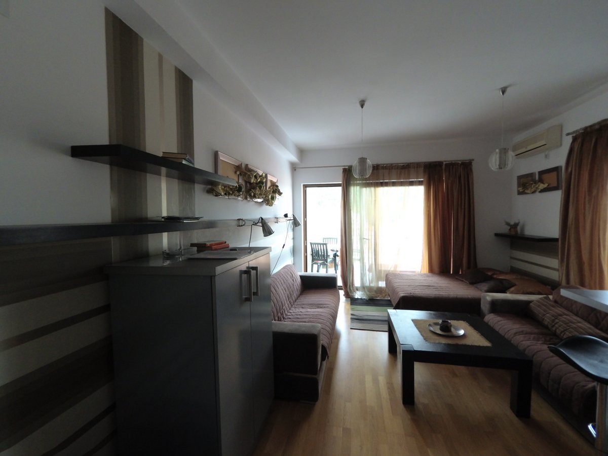 Cozy living room with furniture and access to the terrace in an apartment in Budva, Montenegro. Modern interior with parquet flooring.