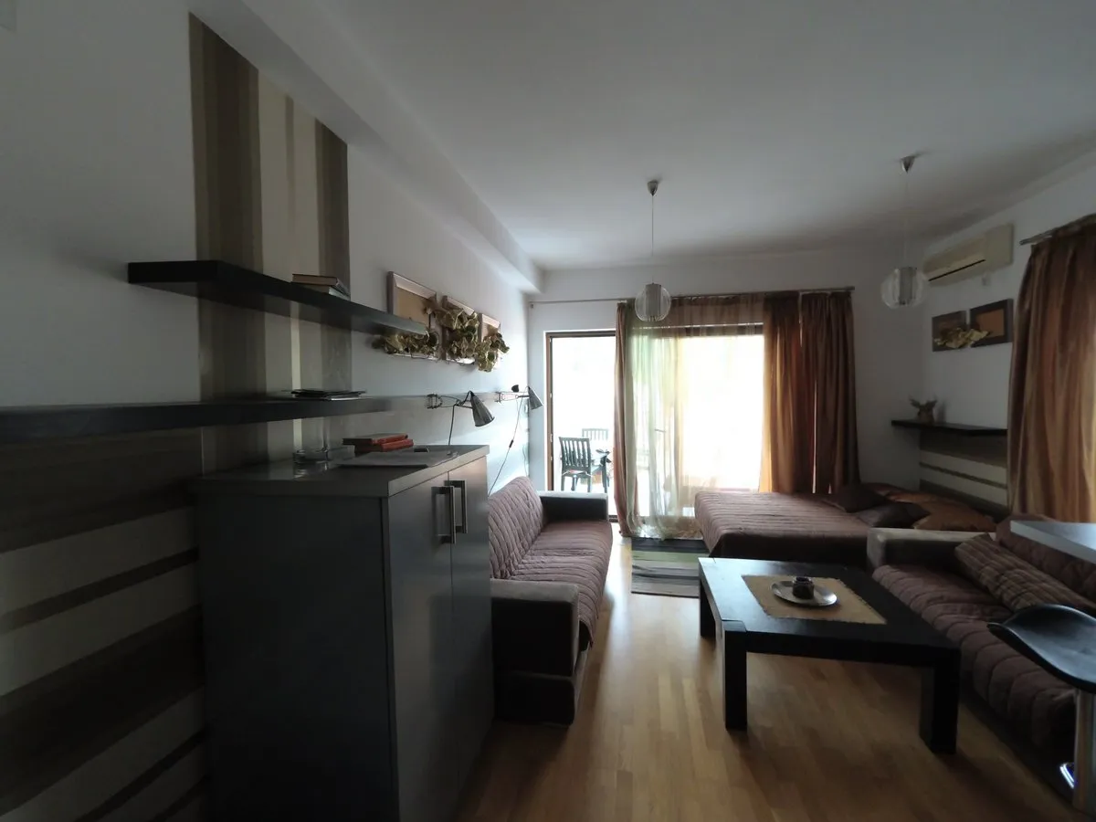 Living room with brown sofas, black coffee table, floating shelves, striped wallpaper and wood floor.