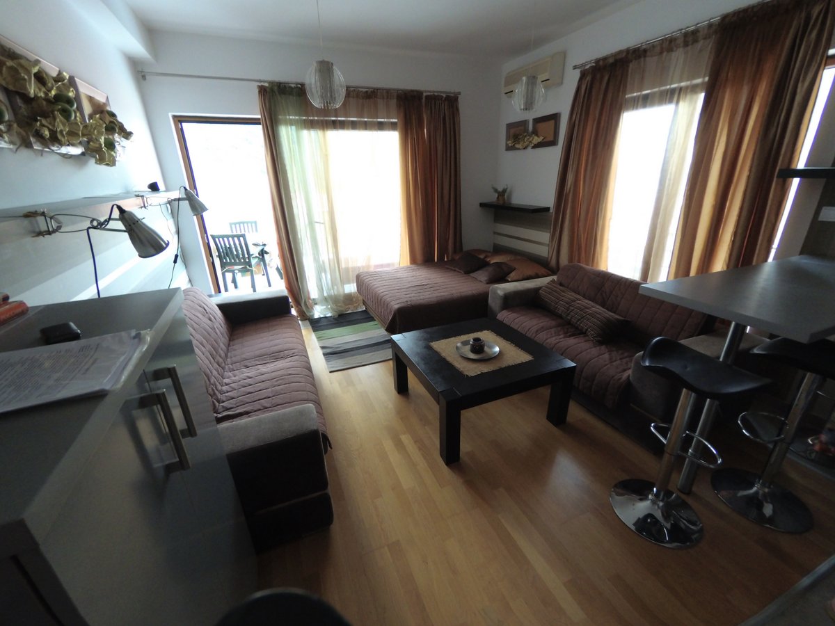 Living room in an apartment in Budva, Montenegro: soft seating, a coffee table, a bar counter, and access to the terrace.