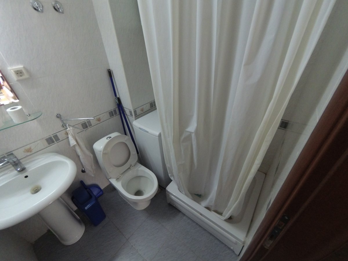 Bathroom in an apartment in Budva, Montenegro: light-colored tiles, plumbing fixtures, shower cabin, and washing machine.