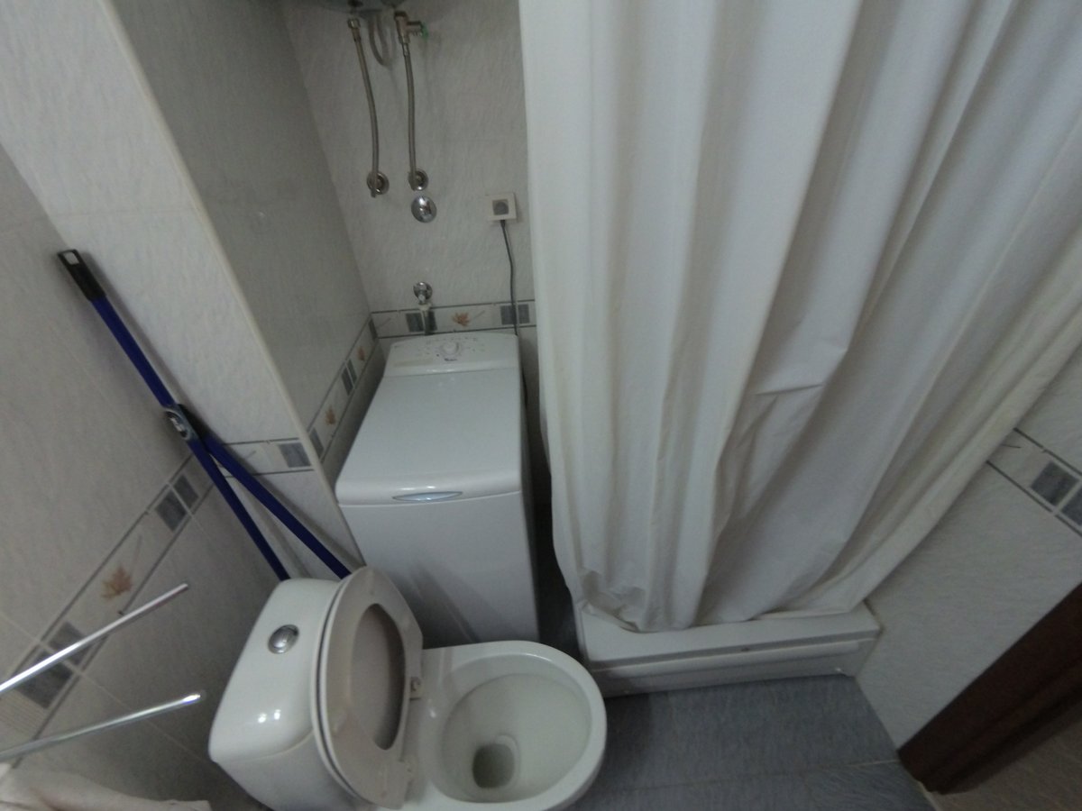 Bathroom in an apartment in Budva, Montenegro: a compact bathroom with a shower cabin, toilet, and washing machine.