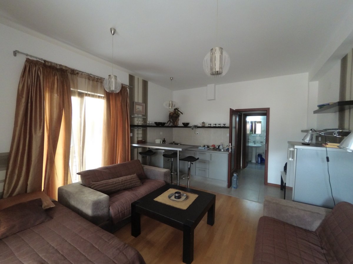 Living room with kitchen in an apartment in Budva, Montenegro: soft furniture, bar counter, bright interior, and access to the balcony.