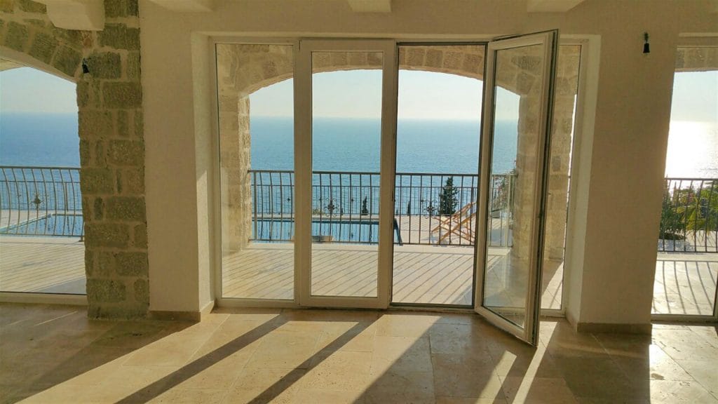 Villa living room in Drobni Pijesak, Montenegro: panoramic sea view, terrace with pool, and stone arch detailing.