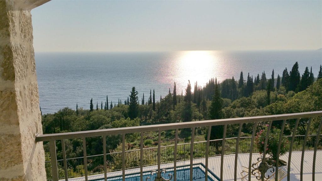 View from the villa balcony in Drobni Pijesak, Montenegro: a panorama of the sea, cypress trees, and a private pool on the terrace.