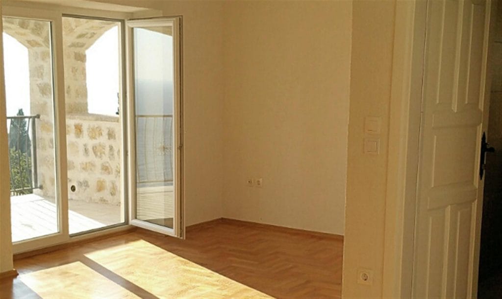 Bright living room with parquet flooring and access to a terrace with sea views in Villa Drobny Pesak, Montenegro.