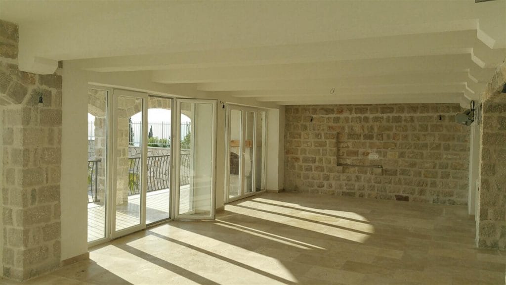 Spacious living room with stone walls and panoramic windows in a villa in Drobni Pijesak, Montenegro.