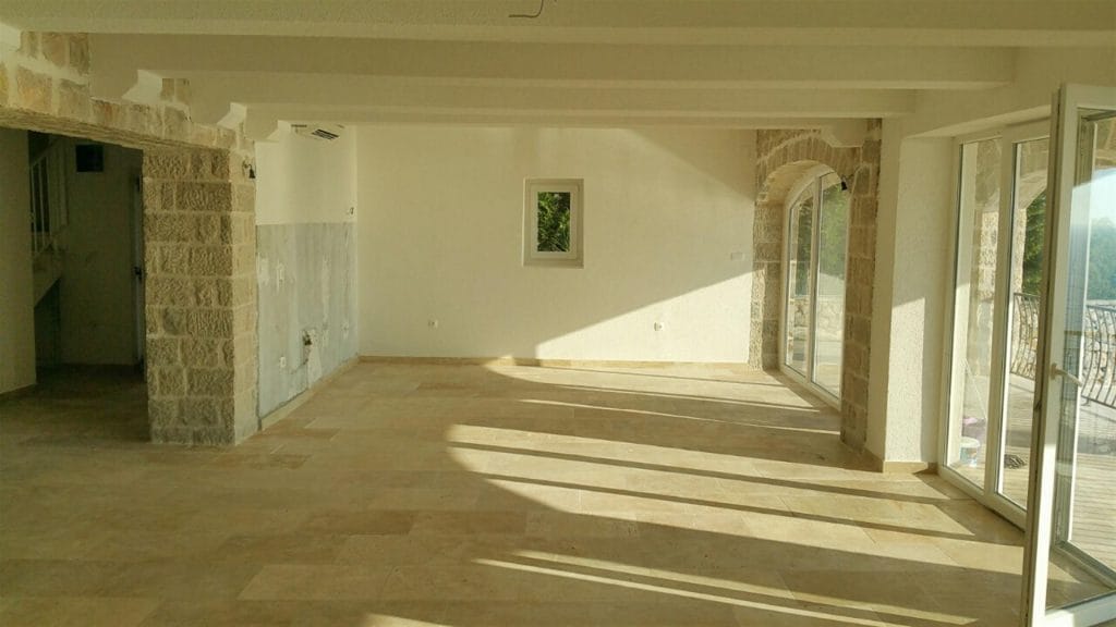 Spacious living room with stone finishes and panoramic windows in a villa in Drobni Pijesak, Montenegro.