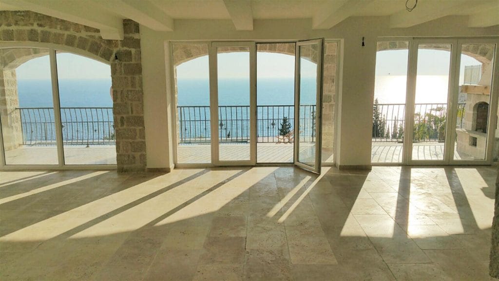 Living room with panoramic sea view and stone finishes in a villa in Drobni Pijesak, Montenegro.
