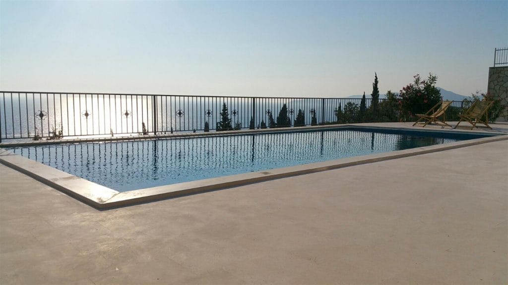 Outdoor pool at a villa in Drobni Pijesak, Montenegro, with panoramic sea views and sun loungers on the terrace.