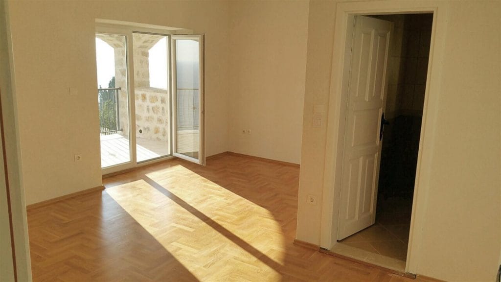 Bright living room with parquet flooring and access to the terrace in the Drobny Piesak villa, Montenegro. Sea view and stone masonry.